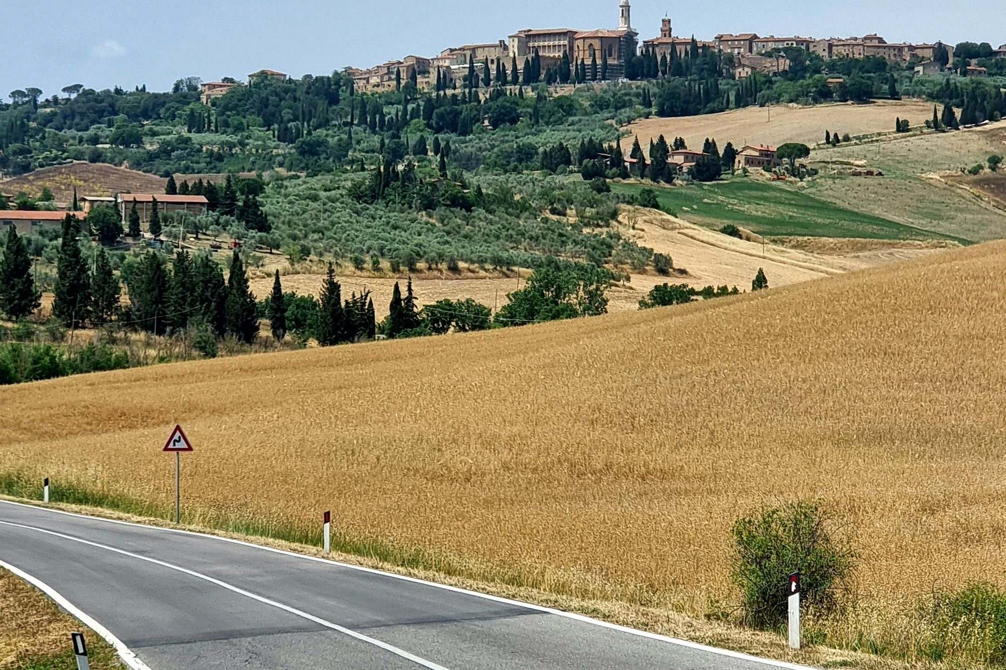 Strada fra campi di grano e colline toscane